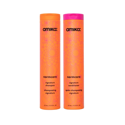 bottle of shampoo and conditioner with black branding on an orange bottle with a pink abstract design. 